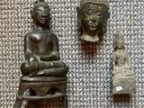 two small statues of buddhas and a buddha statue on a table