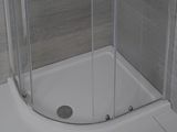 une douche avec une porte en verre, située dans un coin de la salle de bains