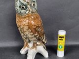 a ceramic owl sitting on a tree stump next to a lip bale