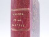an old red book sitting on top of a table next to a white background