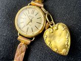 a gold watch with a heart charm attached to it