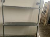 une étagère métallique comportant deux tablettes, dans une pièce