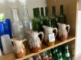 many bottles and pitchers on a shelf in a room