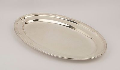 an oval silver tray with a handle on a white surface