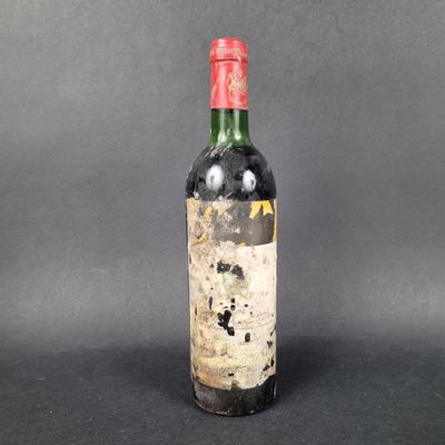 an old bottle of red wine sitting on top of a table