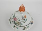 a small orange flower on a white plate with a lid