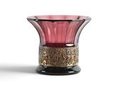un vase en verre rose bordé d'or, posé sur une surface blanche