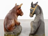 two figurines of a bull and a donkey sitting on a rock