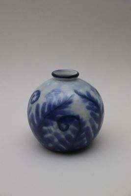 un vase bleu et blanc muni d'un couvercle noir, posé sur une surface blanche