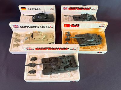 Quatre véhicules militaires miniatures se trouvent dans une boîte posée sur une table