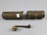 an old brass cylinder and a brass ball on a white surface
