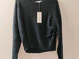 Le pull est suspendu à un cintre accroché au mur.