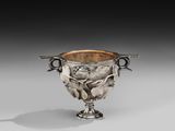 an antique silver cup with two handles and a flower decoration