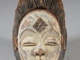 a close up of a wooden mask on a white surface