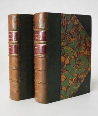 two old books sitting on top of each other on a white surface