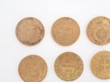 six different types of gold coins are shown on a white surface