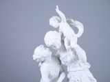 une statue blanche représentant un garçon et une fille, posée sur un socle
