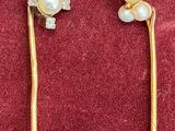 pair of gold tone earrings with pearls and diamonds on a red background
