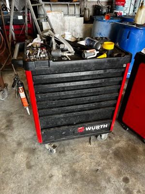 une boîte à outils noire contenant des outils, dans un garage