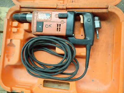 une mallette orange contenant une perceuse et un cordon d'alimentation
