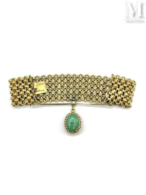 a close up of a gold bracelet with a green stone