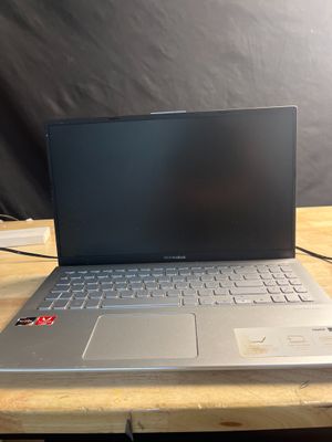 L'ordinateur portable est posé sur une table en bois, sur fond noir.