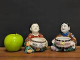 three figurines sitting on a table with an apple in front of them