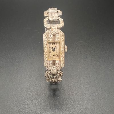 une image représentant une montre en or et diamants posée sur un fond noir