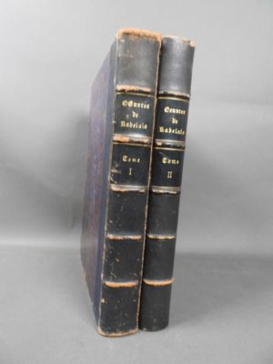 two old books sitting on top of each other on a table