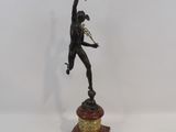 statue en bronze représentant un homme tenant une torche, posée sur un socle en bois