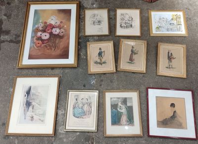many framed pictures on the floor next to a basket of flowers