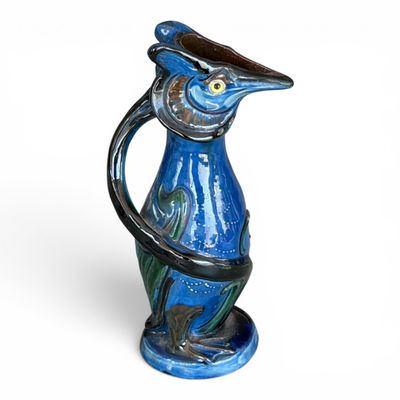 un vase bleu orné d'un oiseau, posé sur un fond blanc