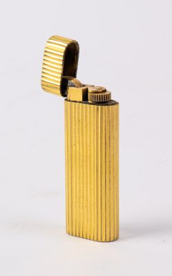 briquet en métal jaune posé sur une surface blanche, avec un fond blanc
