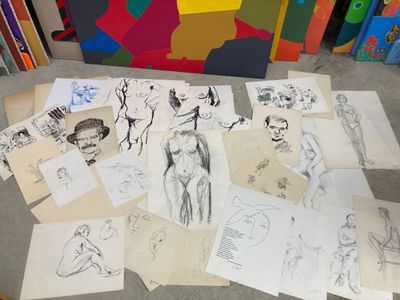 a lot of drawings on the floor next to a pile of books