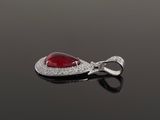 an oval ruby and diamond broochle on a black surface