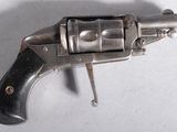 un revolver argenté avec une poignée noire sur une surface blanche