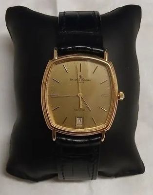 une photo d'une montre en or posée sur un coussin noir
