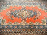an orange area rug with a blue border and a floral design