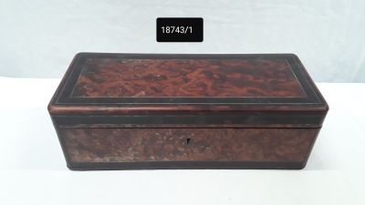 an old wooden box with a black lid on a white table
