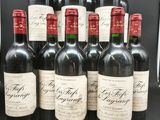 six bouteilles de vin rouge sont alignées sur une table