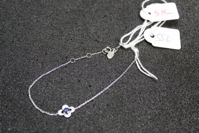 a silver bracelet with a heart on it on a black surface