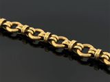 gros plan d'un bracelet en or sur une surface noire