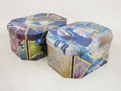 deux boîtes de cartes Pokémon posées sur une surface blanche