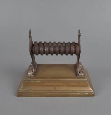 une plaque en laiton ancien avec un socle et une poignée en bois