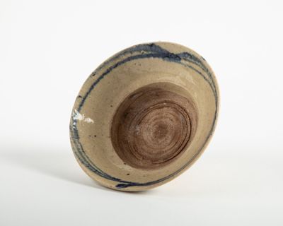 un gros plan d'un bol marron et bleu posé sur une surface blanche