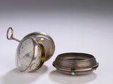 une montre de poche en argent posée à côté d'une bague en argent