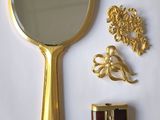 un miroir doré et un ensemble de bijoux en or posés sur une surface blanche