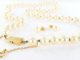 Gros plan sur un collier de perles blanches avec un fermoir en or