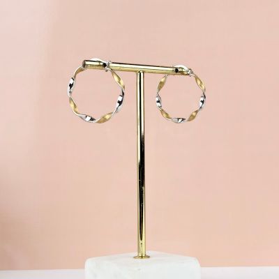 a pair of gold hoop earrings on a marble stand