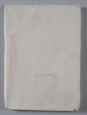 an old book sitting on top of a table next to a white cloth